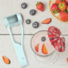 Compact fruit slicer tool beside strawberries, grapes, and blueberries